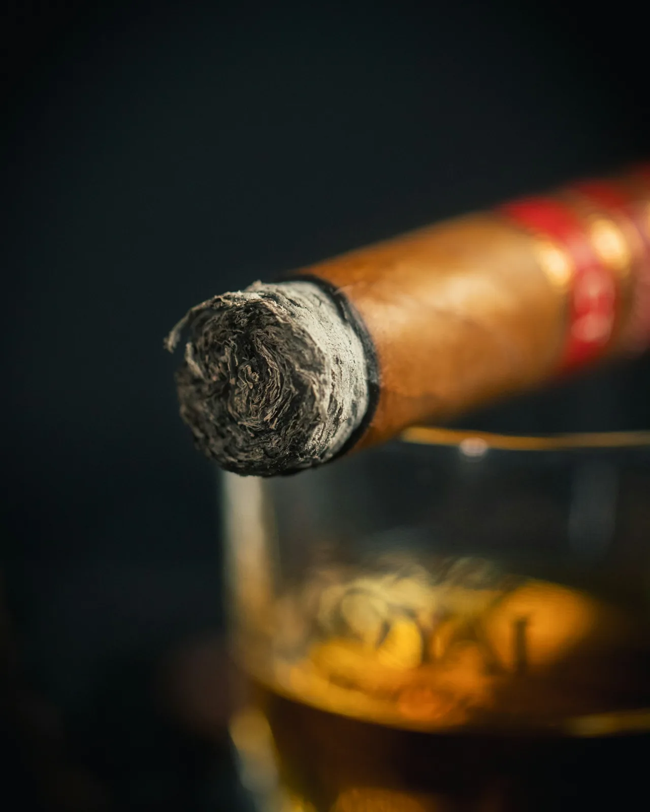 A lit cigar resting on a glass of bourbon